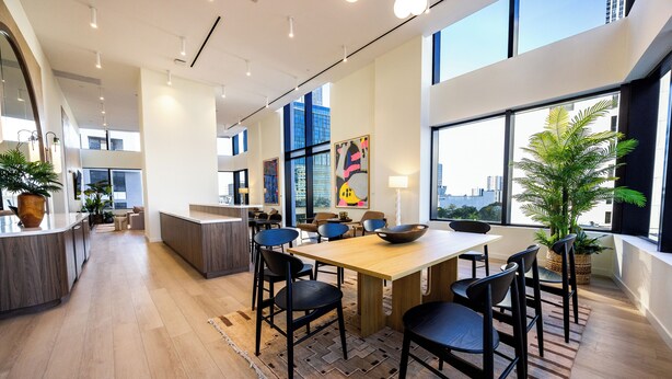A modern interior with a wooden dining table, black chairs, and a large window offering a city view. - District 3704 (Miami)