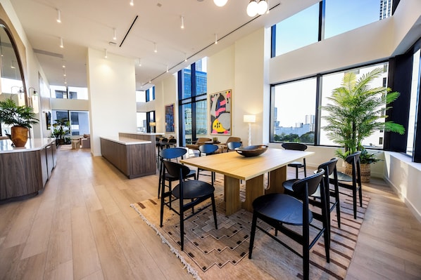 A modern interior with a wooden dining table, black chairs, and a large window offering a city view. - District 3704 (Miami)
