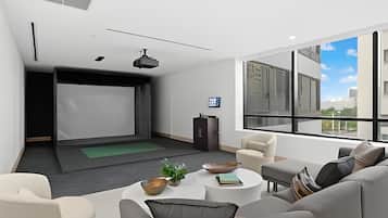 Un salon moderne doté d’un écran de projection, de sièges confortables et d’une grande fenêtre offrant une vue sur la ville.