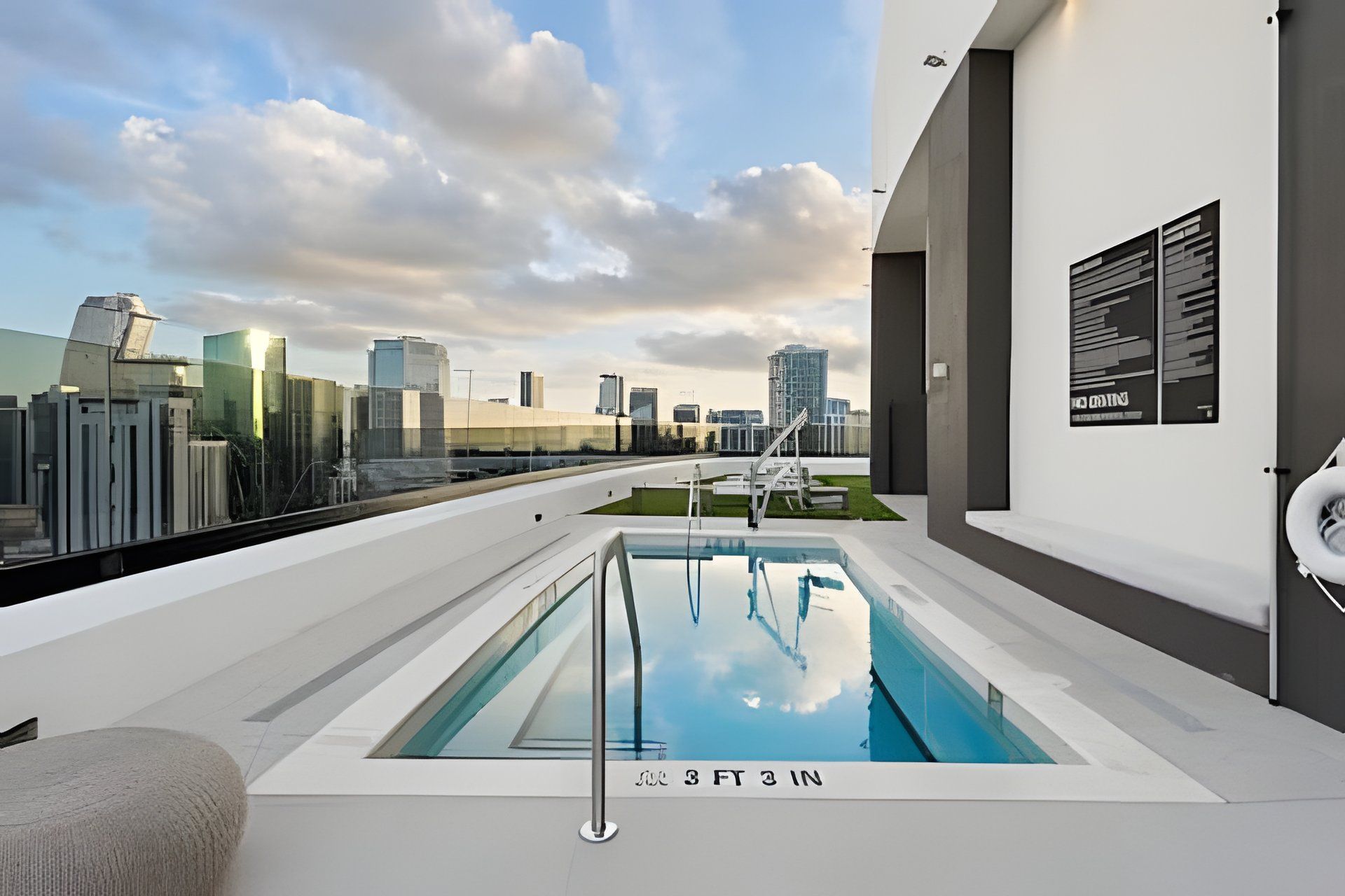 A rooftop pool with a city view, a lounge area, and a lifebuoy on the wall.