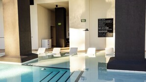 A clear indoor swimming pool with marked lanes, a sign indicating pool rules, and a restroom sign. - District 3704 (Miami)
