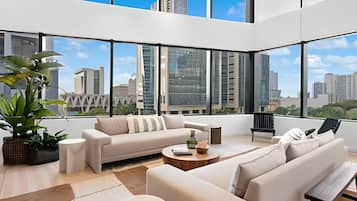 A modern living room with a sofa set, a coffee table, and a view of the cityscape through large windows.