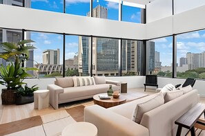A modern living room with a sofa set, a coffee table, and a view of the cityscape through large windows. - District 225 - Rooftop Pool - Gym - Parking - Downtown Miami (Miami)