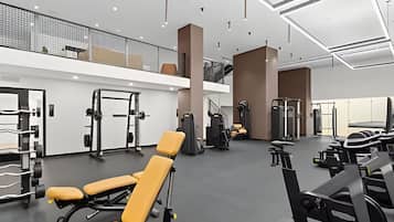 A modern gym with various exercise equipment, a mezzanine level, and a spacious layout.