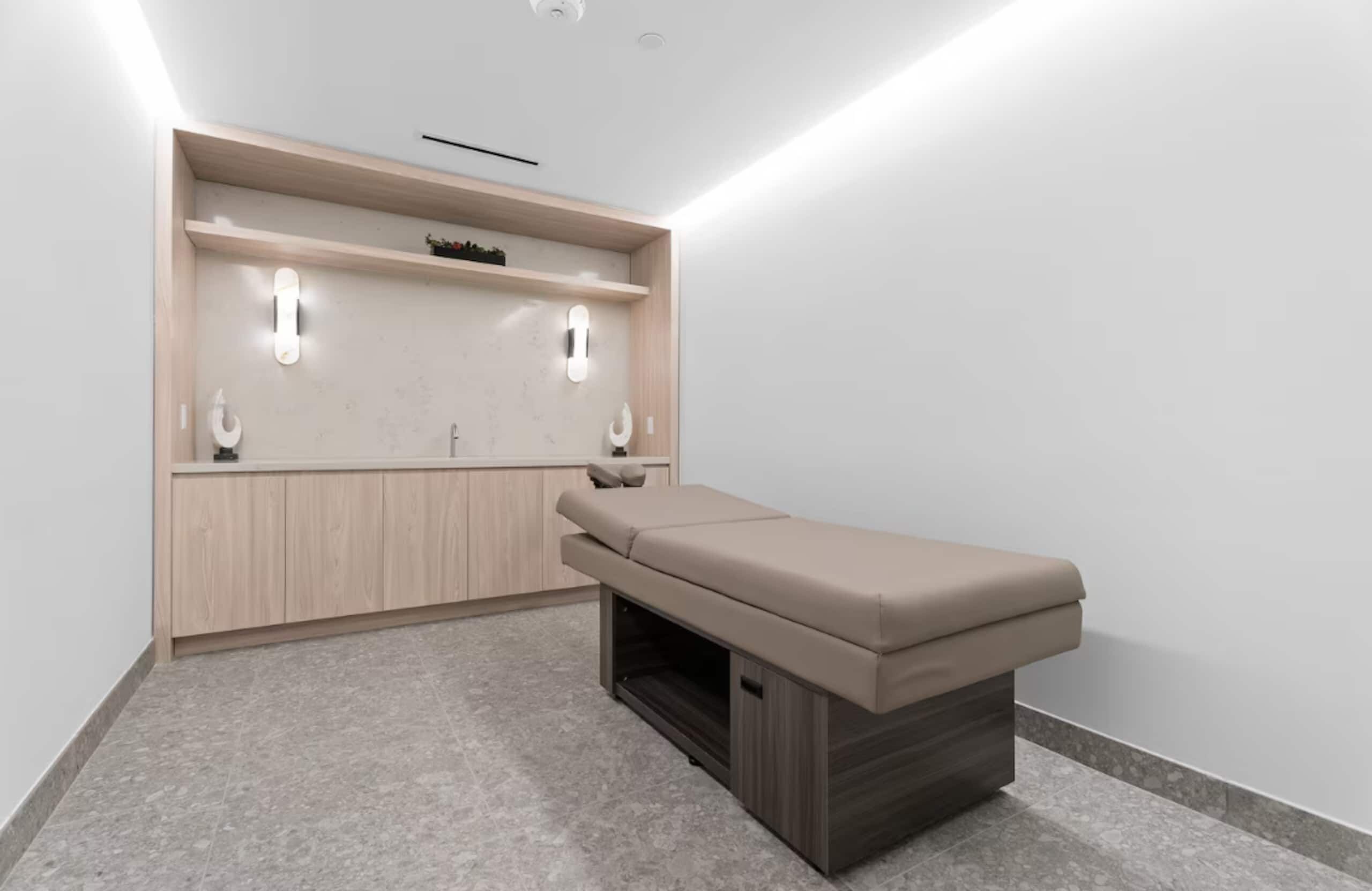 Quarto com armário de madeira, um banco e duas luminárias fixadas na parede.