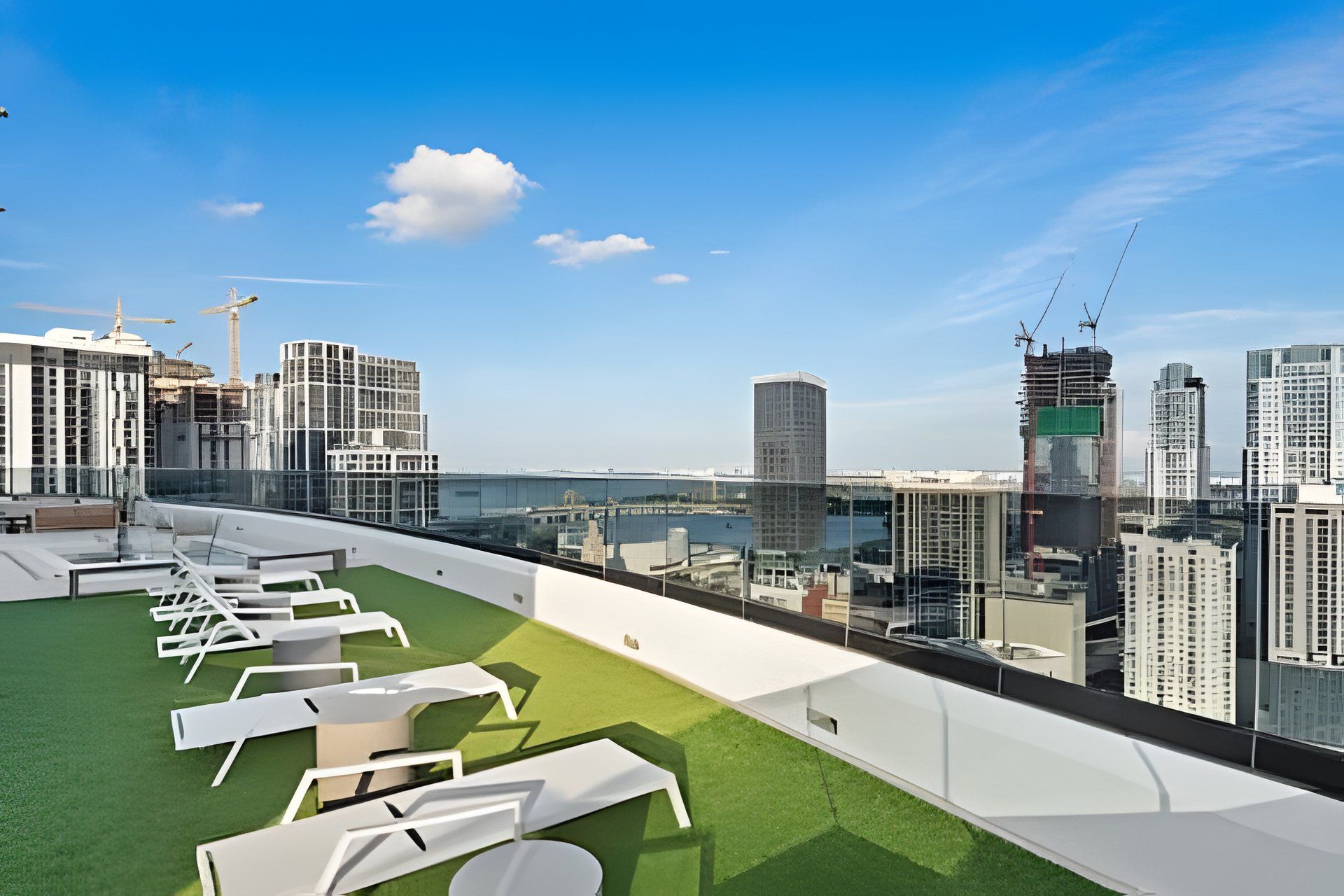 A rooftop terrace with lounge chairs and a view of the cityscape.
