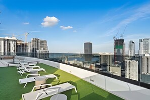 Eine Dachterrasse mit Liegestühlen und Blick auf die Stadtlandschaft.