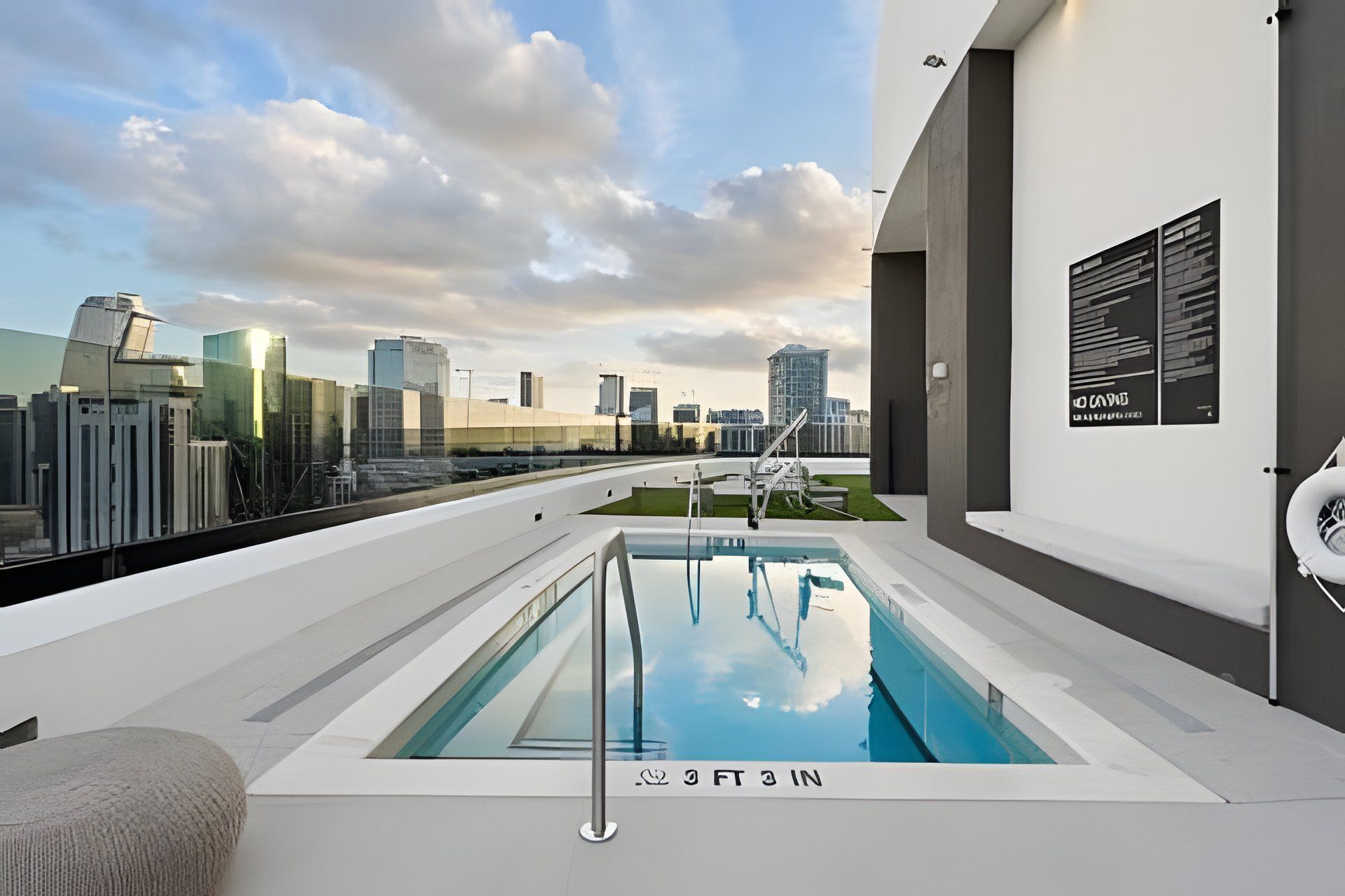 A rooftop pool with a city skyline view, a modern building facade, and a clear sky.