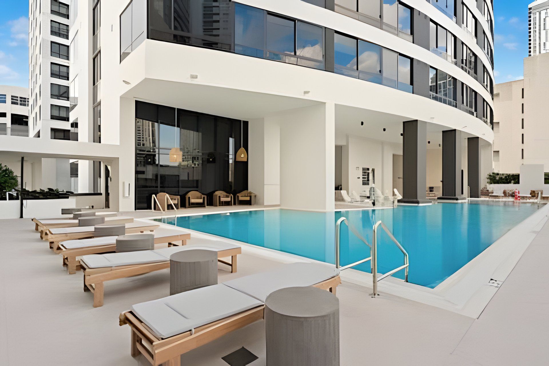 A modern hotel pool area with sun loungers and a clear blue pool.