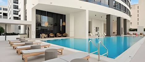 A modern hotel pool area with sun loungers and a clear blue pool.