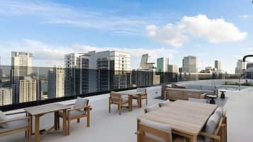 Terraço no telhado com área de estar ao ar livre e vista para o horizonte urbano.