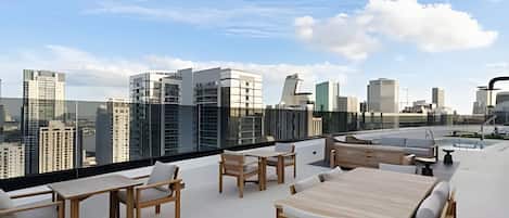 Una terraza en la azotea con mobiliario exterior y vistas a un horizonte urbano.