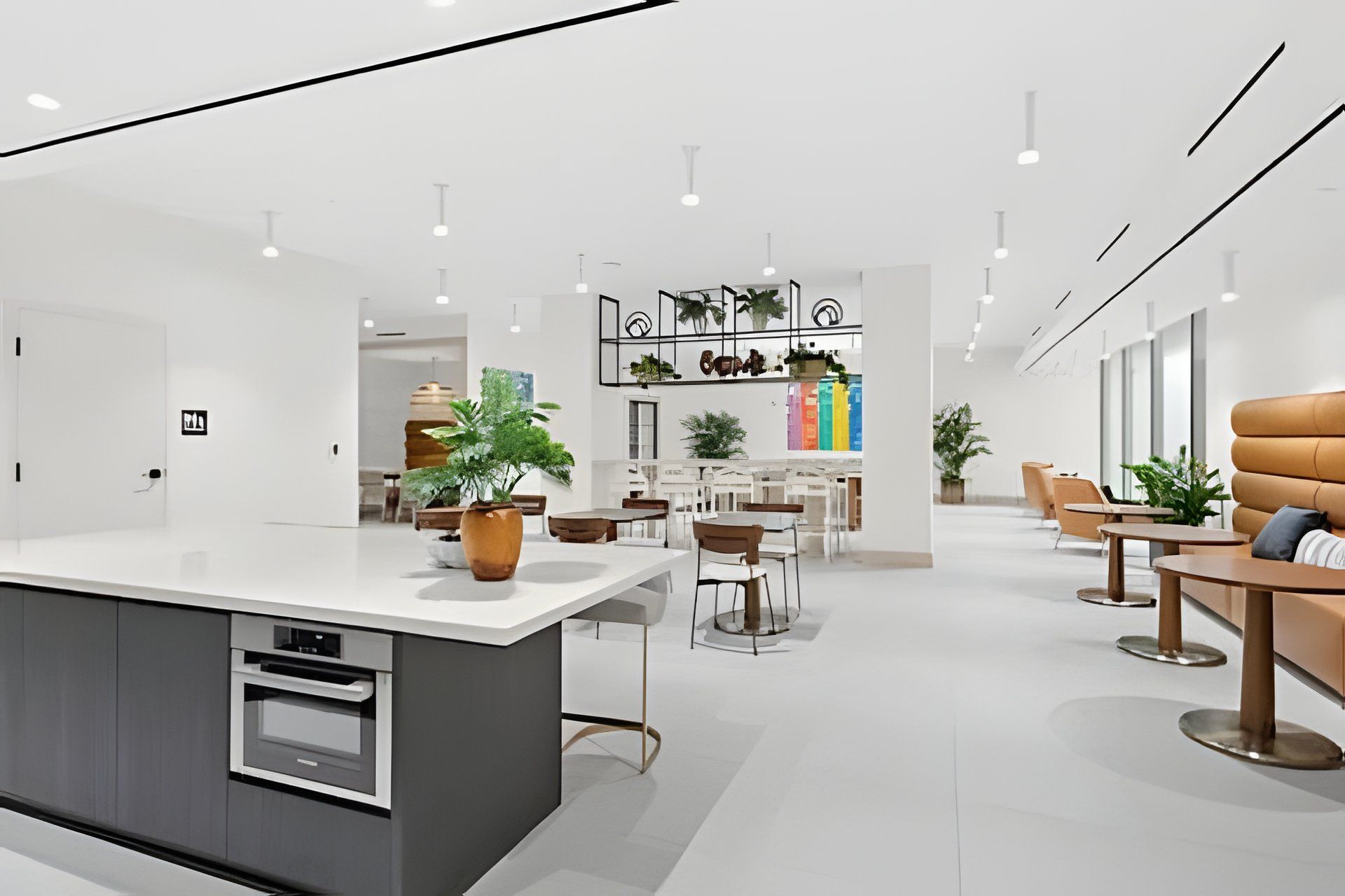 A modern kitchen with a central island, dining area with chairs and tables, and a bar area with plants.