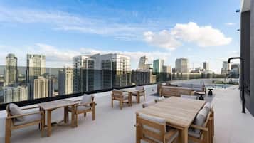 A rooftop terrace with outdoor furniture, a pool, and a city skyline view.