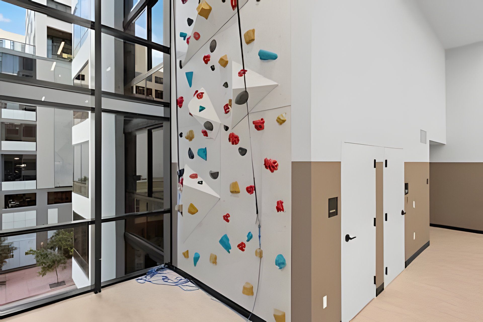 Un intérieur moderne avec un mur d’escalade, de grandes fenêtres et un couloir doté de portes.