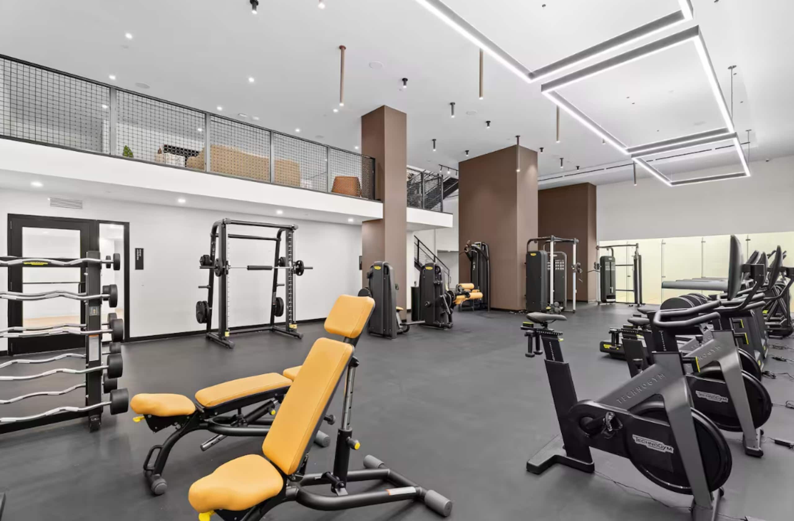 Academia moderna com diversos equipamentos de exercício, incluindo aparelhos de musculação e pesos livres.
