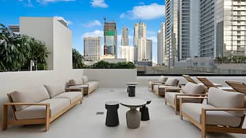 A rooftop terrace with multiple seating areas, a view of the city skyline, and a mix of modern and traditional architecture.