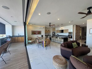 A modern kitchen with a central island, bar seating, and a dining area with chairs. - Fabulous Penthouse with Ocean & Mountain Views (Puerto Vallarta)