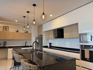 A modern kitchen with a central island, stainless steel appliances, and pendant lighting. - Fabulous Penthouse with Ocean & Mountain Views (Puerto Vallarta)