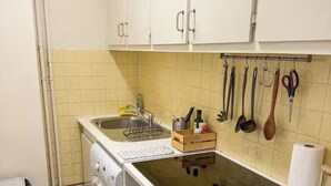 A compact kitchen with a washing machine, a sink, and a countertop with various utensils. - Cozy studio in the heart of Paris - Eiffel Tower (Paris)