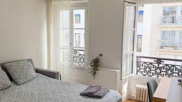 Une chambre à coucher comprenant un lit, un bureau, une chaise, un radiateur et une fenêtre donnant sur l’extérieur.