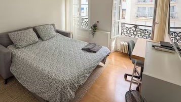 Ein Schlafzimmer mit Bett, Schreibtisch und Blick ins Freie.