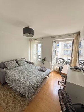 Ein Schlafzimmer mit Bett, Schreibtisch und Blick ins Freie.