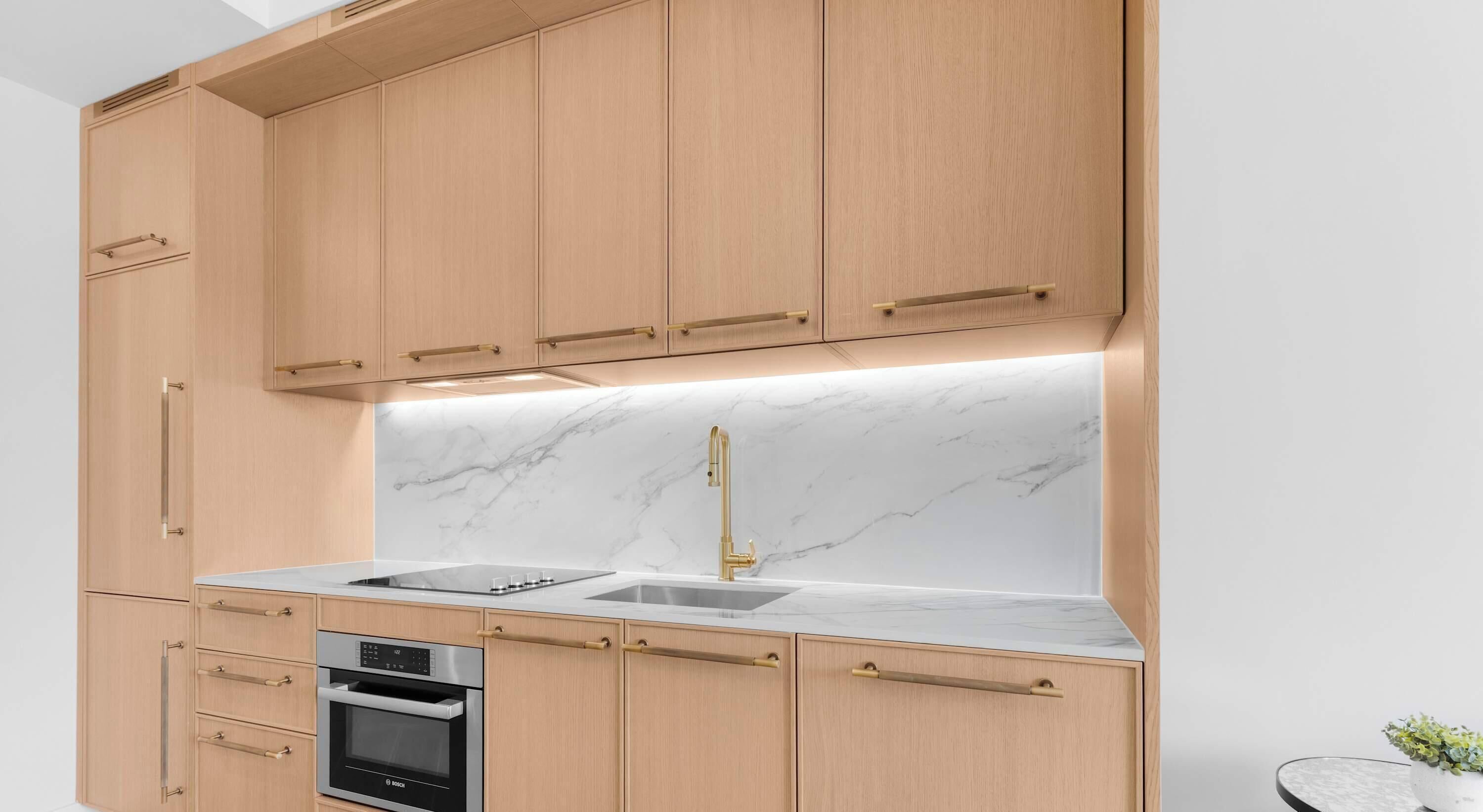 Een moderne keuken met houten kastjes, een roestvrijstalen Bosch oven, een marmeren spatwand en een gouden kraan.