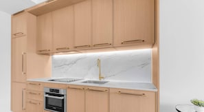 Une cuisine moderne avec des meubles en bois, un four Bosch en acier inoxydable, un dosseret en marbre et un robinet doré.