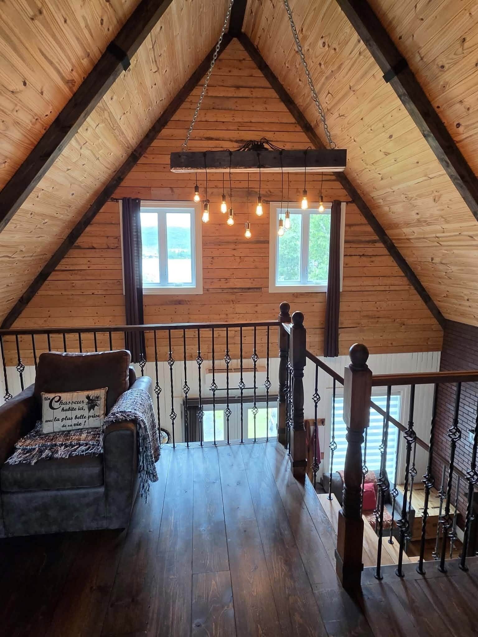 A cozy attic room with wooden walls, a wooden staircase, and a cushioned bench.