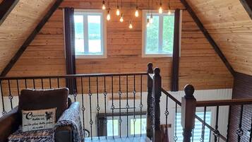 A cozy attic room with wooden walls, a wooden staircase, and a cushioned bench.
