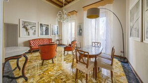 A dining area with a round table, chairs, a red sofa, and a chandelier. - The Grammar Teacher's House - Historic Residence (Prato)