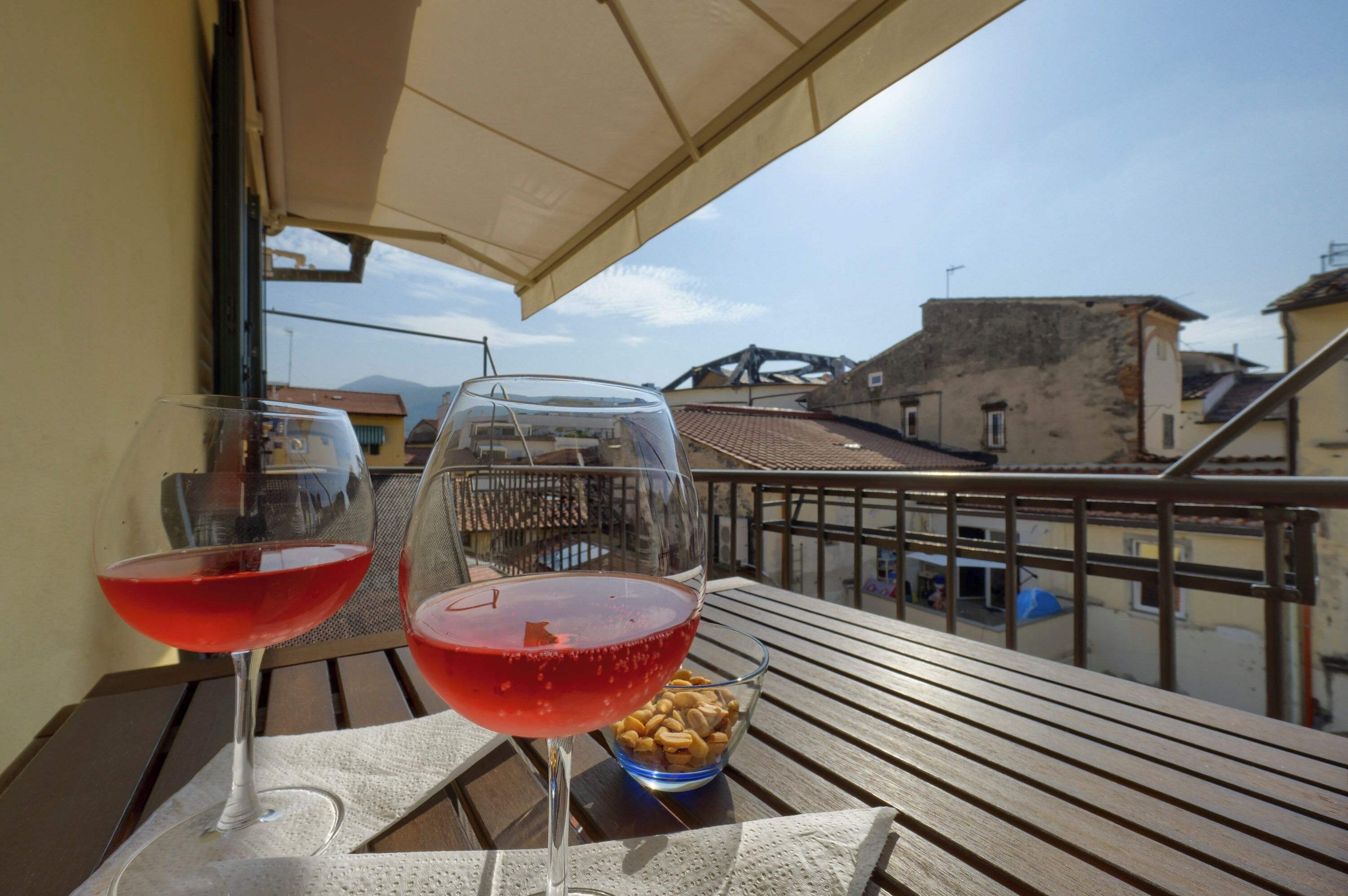 Un balcone con due bicchieri da vino e una ciotola di frutta secca.