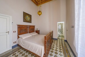A bedroom with a wooden bed, a bedside table, a hanging light fixture, a framed picture on the wall, and a patterned floor. - The Grammar Teacher's House - Historic Residence (Prato)
