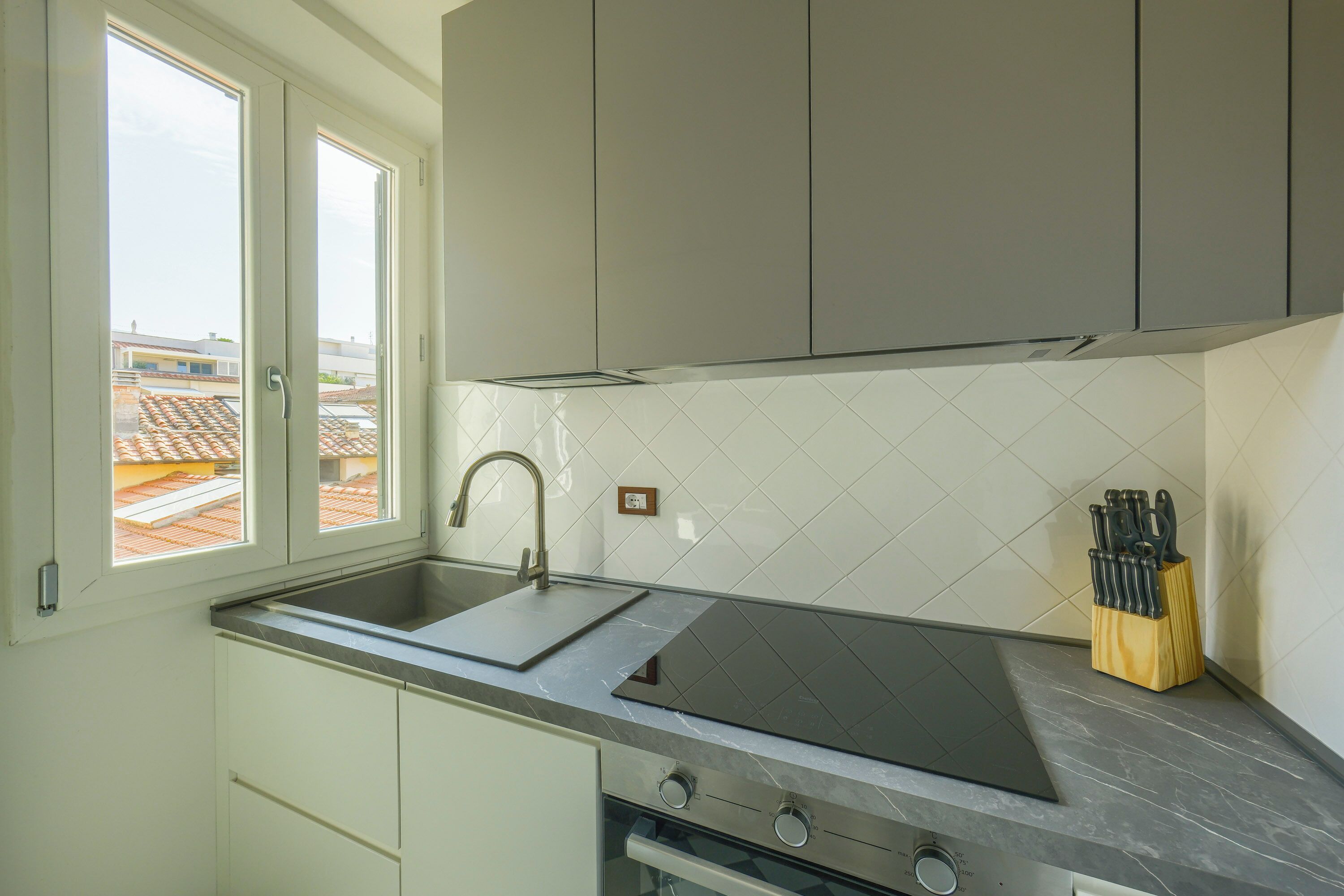 Una cucina con finestra, lavello, fornello e un portachiseli.