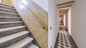 A staircase with marble steps and a handrail, leading to a hallway with a checkered floor and a patterned wall. - The Grammar Teacher's House - Historic Residence (Prato)