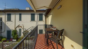 A balcony with a table and chairs, a view of a building with shutters, and a clear sky. - The Grammar Teacher's House - Historic Residence (Prato)