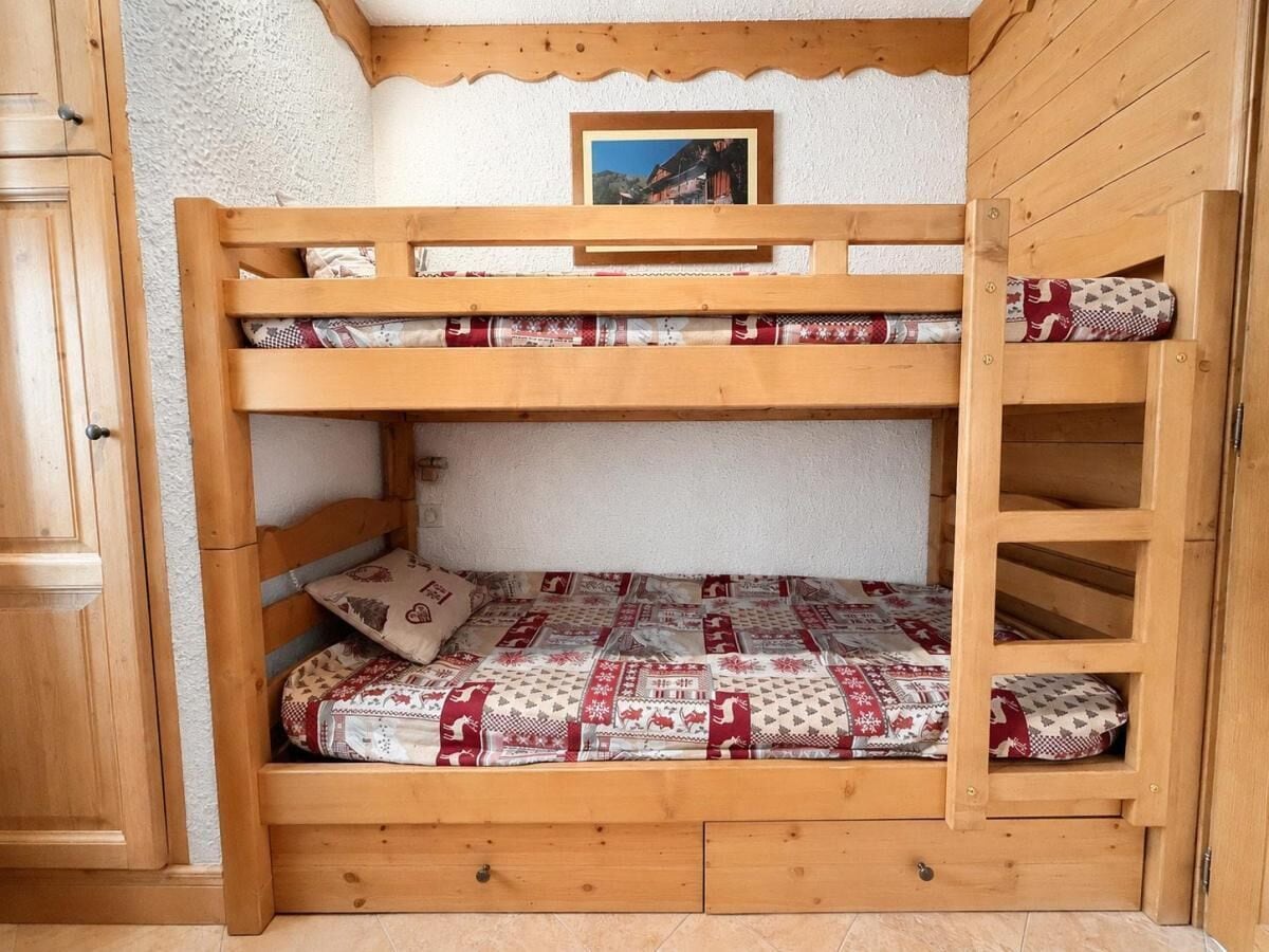 A bunk bed with a wooden frame, a quilted mattress, and a pillow with a patterned design.