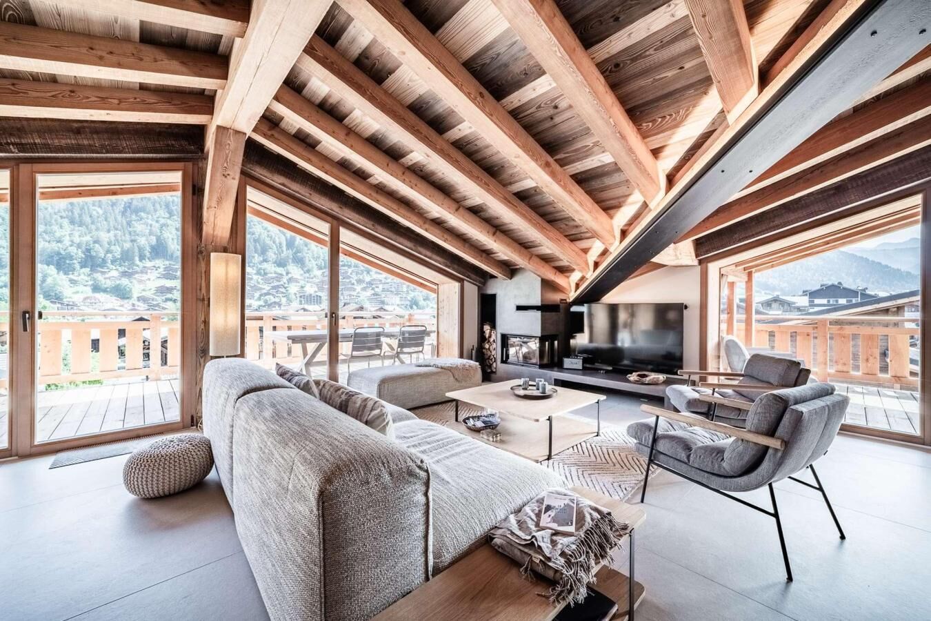 A spacious living area with a high ceiling, large windows, and a fireplace.