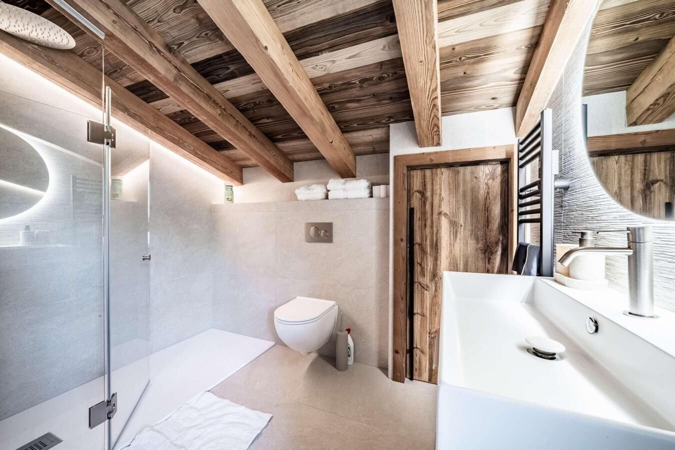 Ein modernes Badezimmer mit Duschkabine aus Glas, einer weißen Toilette und einem großen Waschbecken mit Spiegel.