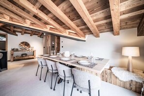 Ein Essbereich mit einem langen Tisch, gedeckt für sechs Personen, Holzbalken an der Decke und einem runden Spiegel auf einer Konsole.