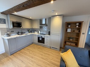 A modern kitchen with grey cabinets, a built-in oven, and a wooden ceiling. - The Traveller`s Loft, The Crown Inn (Cerney Wick)