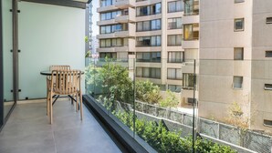 Un balcon doté d’une table et de chaises, offrant une vue sur un immeuble moderne avec de nombreux balcons.