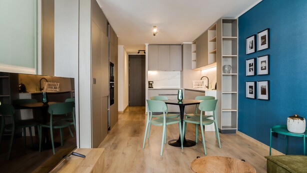 Une cuisine moderne avec un coin repas, comprenant une table et des chaises en bois, une machine à café et un meuble contenant un four à micro-ondes.