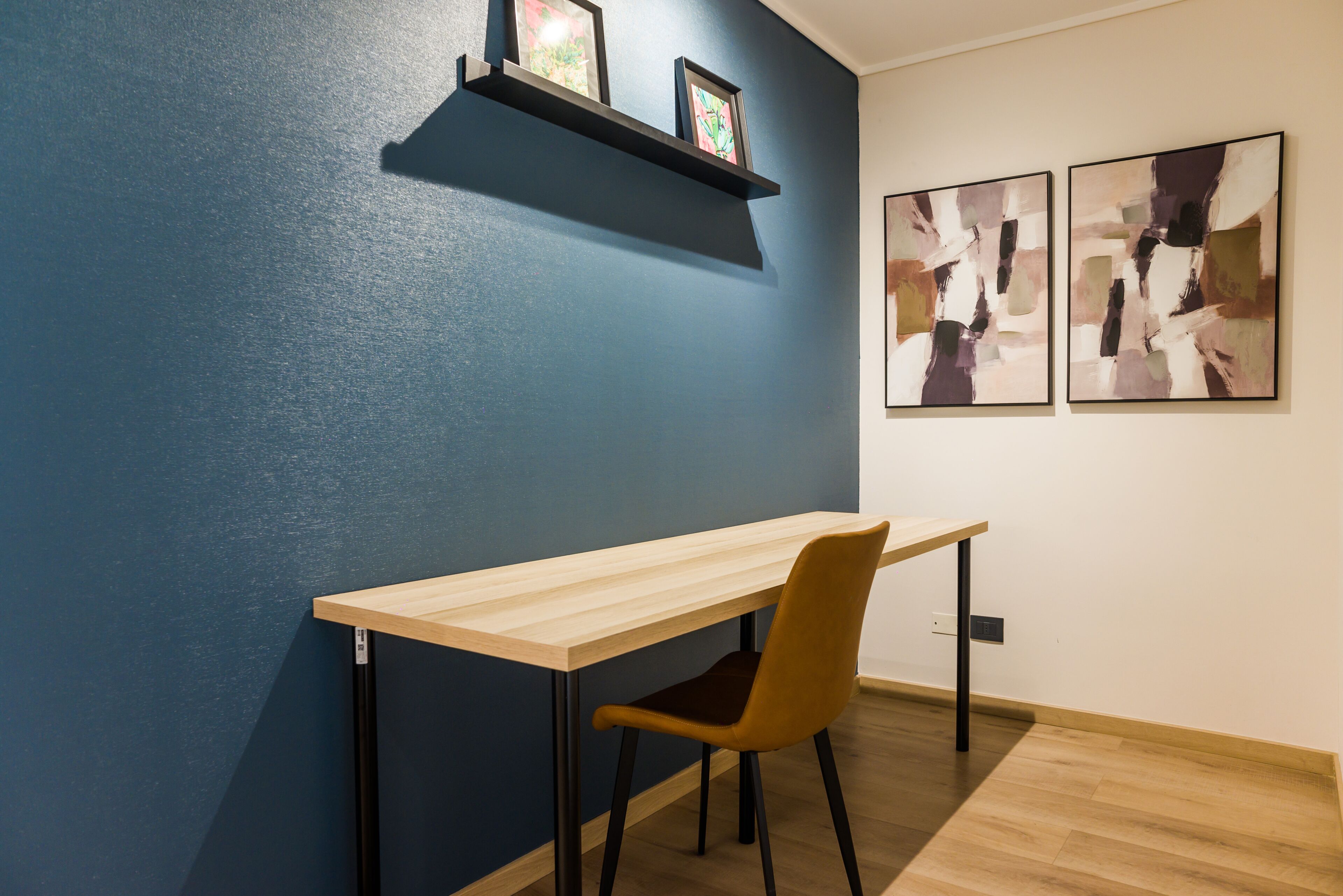 Una habitación con escritorio, silla y dos cuadros en la pared.