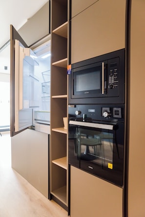A kitchen with a built-in microwave and oven, a wooden cabinet, and a glass door refrigerator. - Chic Apartment in Las Condes (Las Condes)