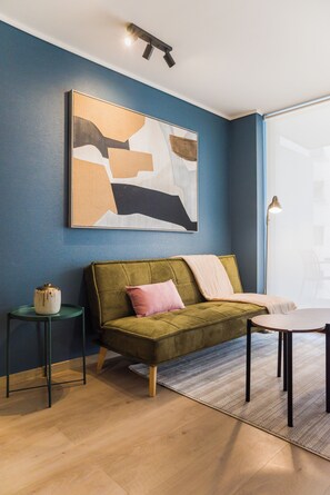 A modern living room with a green sofa, a small side table, a coffee table, and a large abstract painting on the wall. - Chic Apartment in Las Condes (Las Condes)