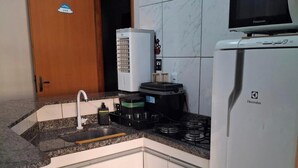 A kitchen with a built-in microwave, a stove, and a refrigerator. - Located in Bairro Turista II, Flat 408 in Caldas Novas, 600 meters from Shopping Singapura. (Caldas Novas)