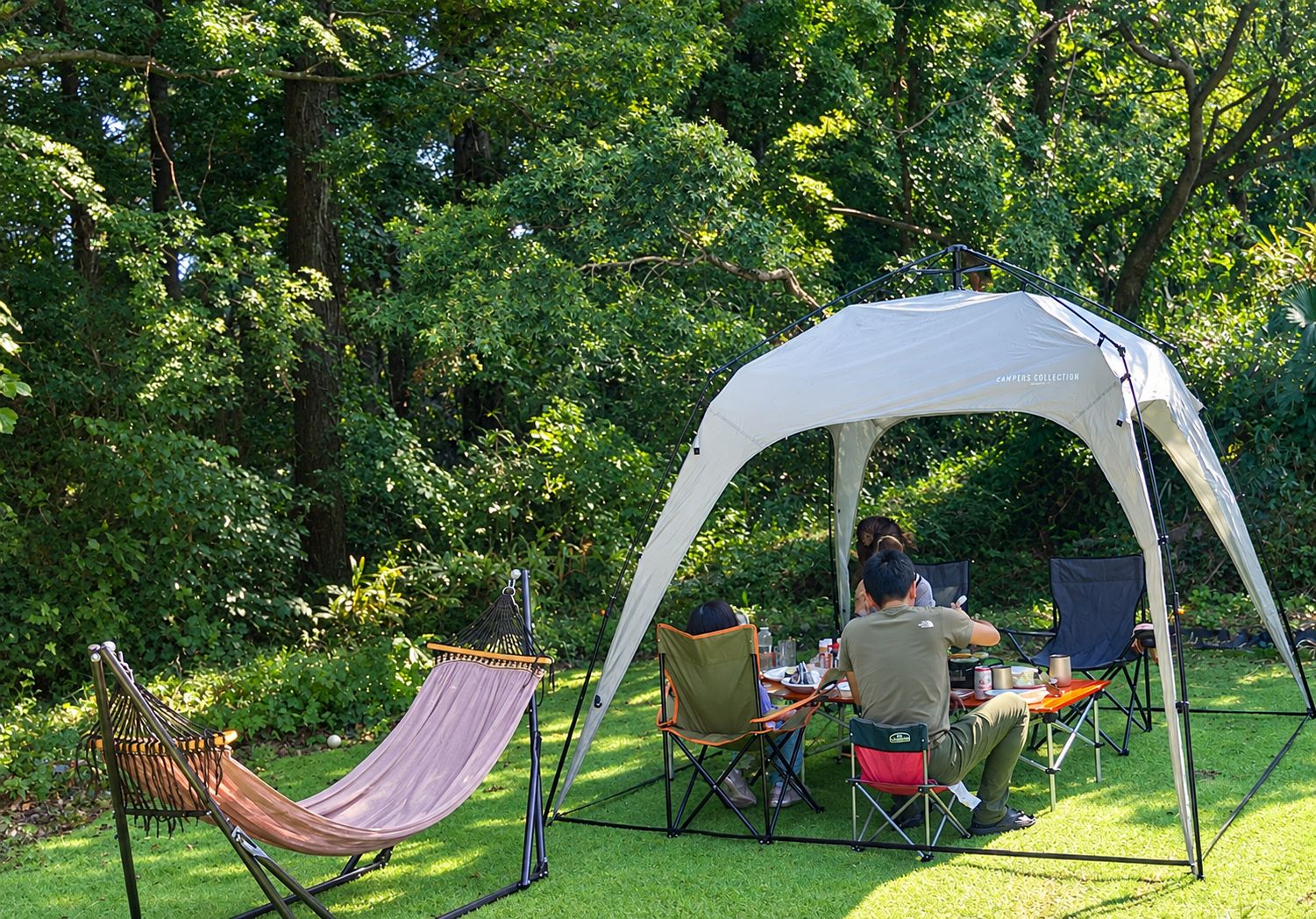 A camping setup with a tent, a hammock, and two chairs.