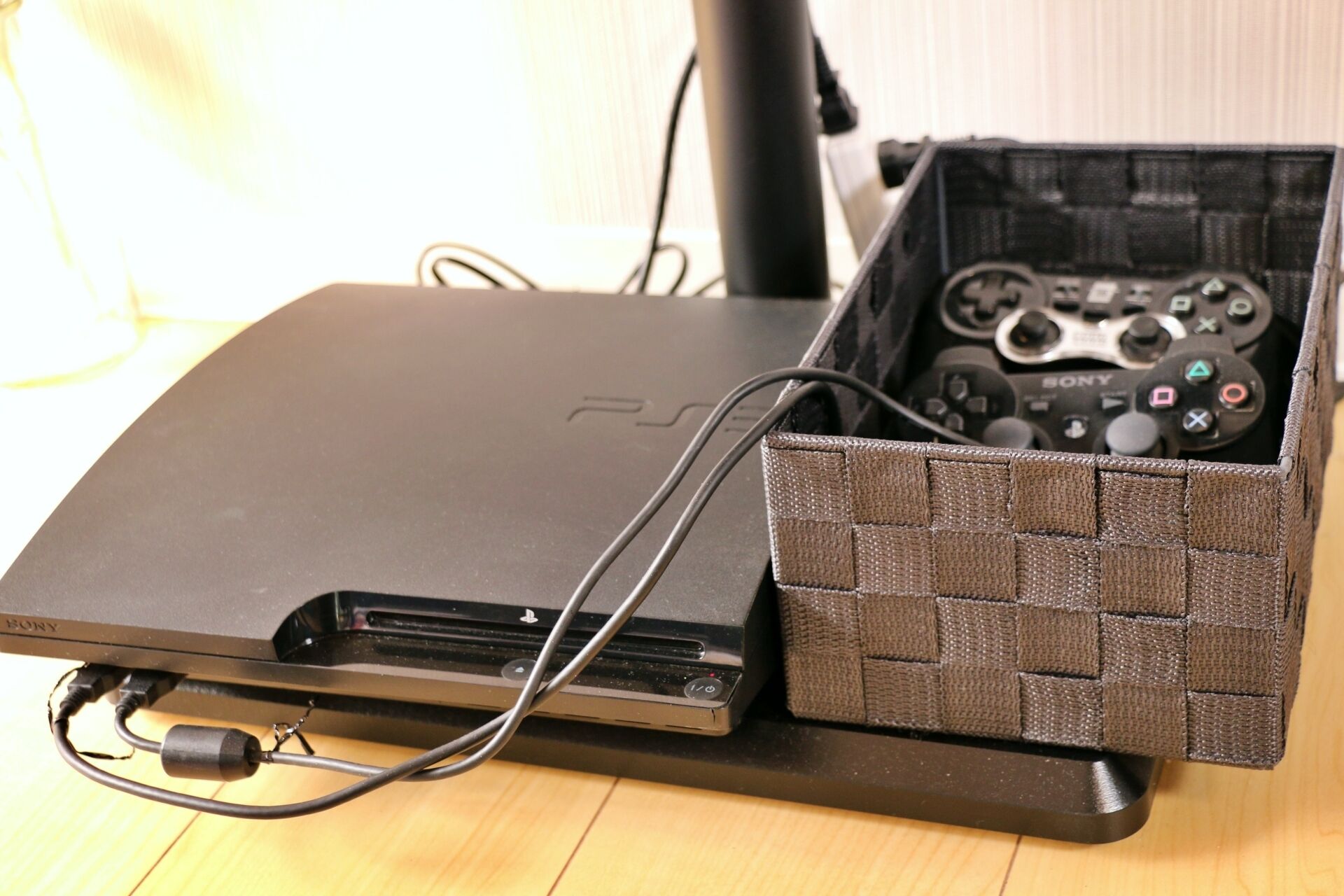 A PS4 console with a controller inside a woven fabric case, connected to a monitor.